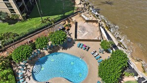 Eine Vogelperspektive eines Resorts mit Swimmingpool, Liegestühlen und Strand.