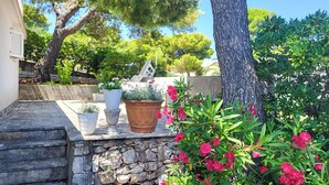 A stone staircase leading to a patio with potted plants and a view of trees.