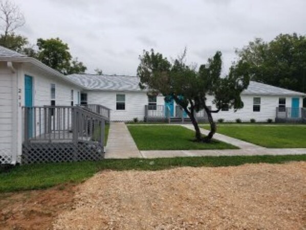 A row of single-story mobile homes with a fenced front yard and a tree in the center. - The Private Place- unit 1 (Alvin)
