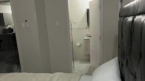 Ein Schlafzimmer mit einem großen Bett, einer Kopfteil und einem zur Badezimmertür führenden Durchgang.