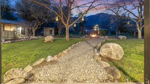 Un jardin aménagé avec un chemin de gravier, de gros rochers et des arbres.