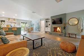Una sala de estar moderna con chimenea, un comedor y una cocina.