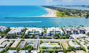 Vista aérea de un complejo turístico en la costa con varios edificios, una playa y un muelle.