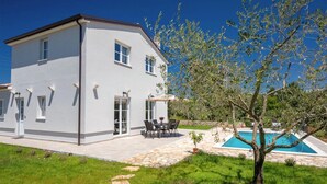 Une maison moderne à deux étages, dotée d’une terrasse, d’une piscine et d’un petit arbre.
