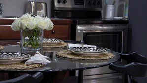 A dining table set with white roses in a glass vase, black and white patterned plates, and woven placemats. - Villa Torre II (Belize City)