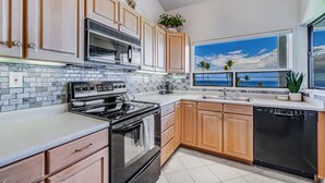 Una cocina moderna con un ventanal grande, una estufa y armarios de madera.