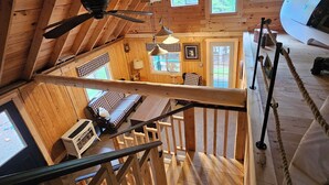A wooden cabin with a loft bedroom, a dining area, and a kitchen. - Spacious cabin on beautiful Long Lake w/waterfront view, private dock, fire pit. (Princeton)
