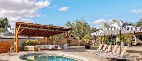 A swimming pool with lounge chairs and a covered seating area.