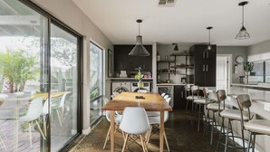 Une cuisine moderne avec une table à manger en bois, des chaises blanches et des luminaires suspendus.