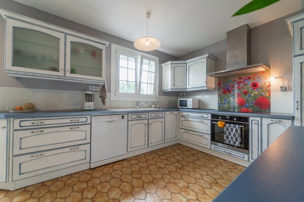 A kitchen with white cabinets, a microwave, a stove, and a sink. - Champ de Gain: family home with swimming pool 10 minutes from Futuroscope (Saint-Georges-lès-Baillargeaux)