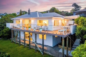 Uma casa de dois andares com varanda, deck de madeira e área de estar externa.
