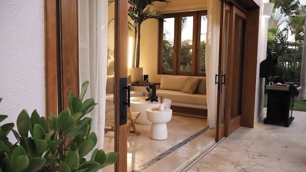 An open door leading to a living area with a sofa, coffee table, and a potted plant.