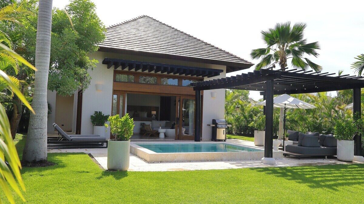 Ein modernes Haus mit Pool, Sitzgelegenheit im Freien und üppigem Grün.