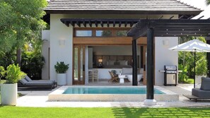 Et moderne hus med pool, udendørs møbler og en pergola.