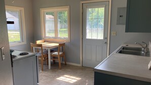 Una cocina compacta con estufa, lavamanos y una zona de comedor con mesa y sillas.