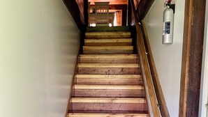 A wooden staircase with a metal handrail and a fire extinguisher mounted on the wall.
