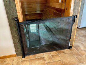 Una habitació amb sòl de fusta, una porta amb mosquitera negra i una paret amb rajoles.