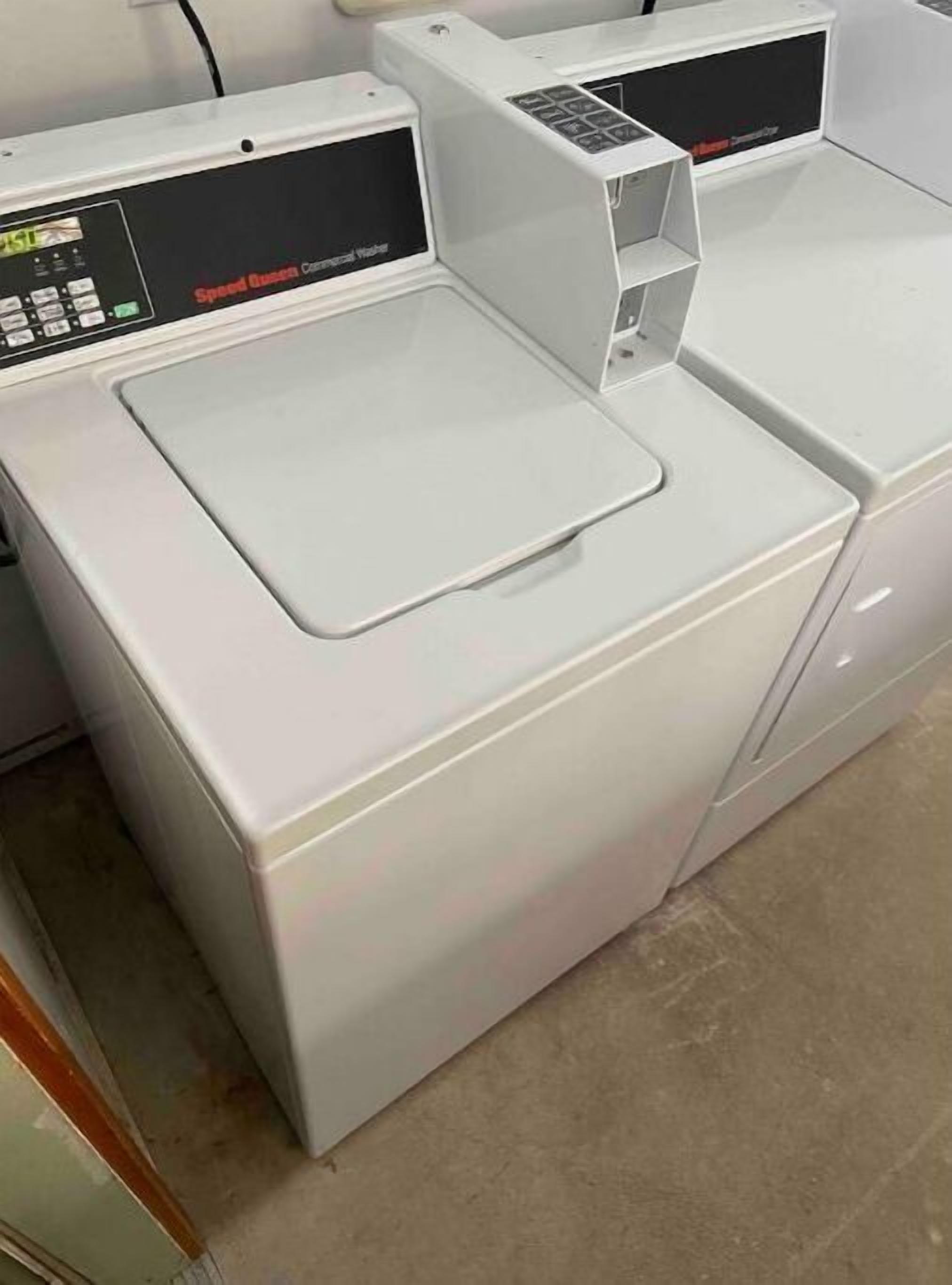 Eine weiße Waschmaschine, vorne gesehen, mit Bedienfeld und einer Klappe zum Beladen von oben.