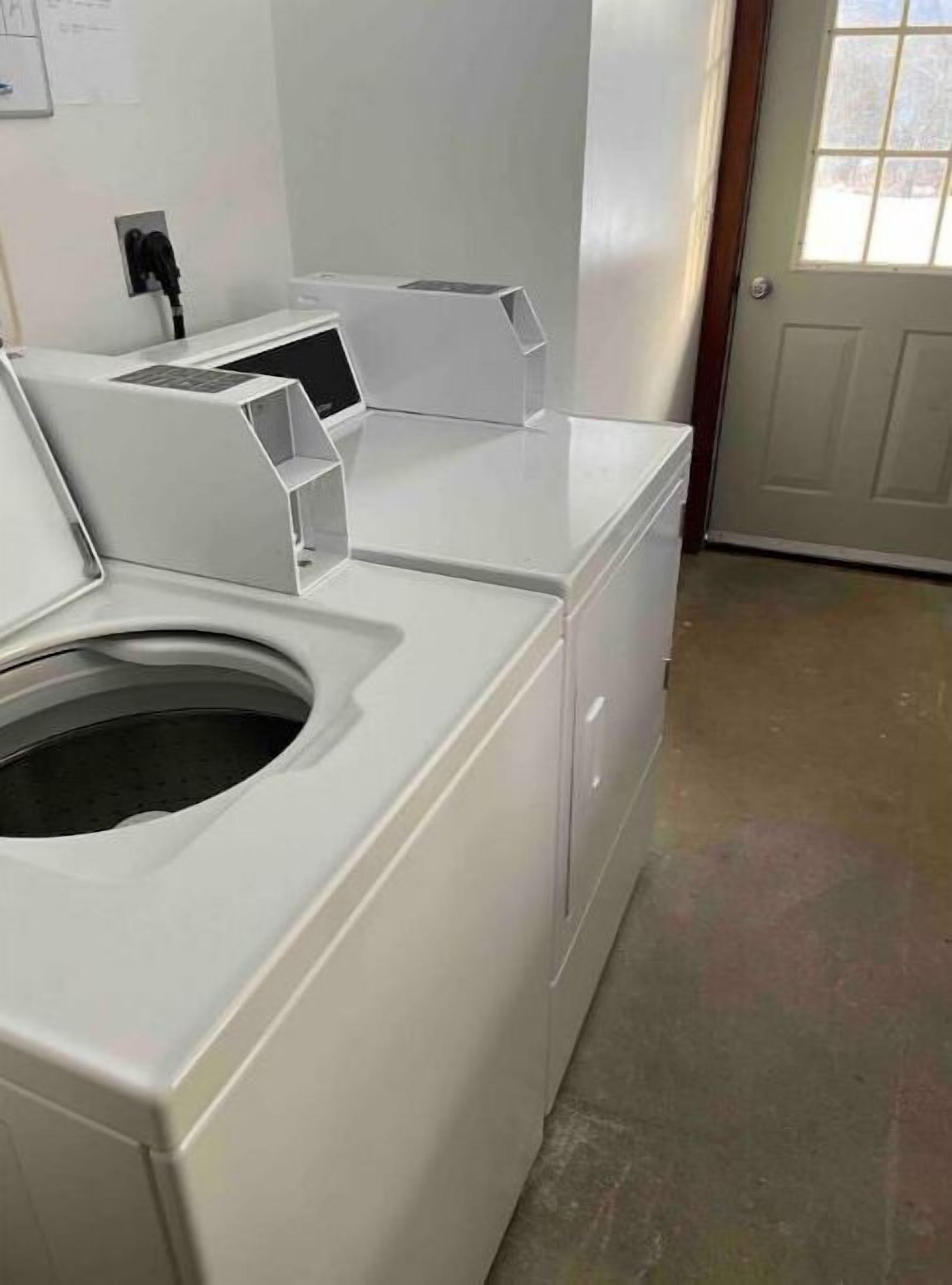 A laundry room with stacked washers and dryers, a power outlet, and a door with a window.