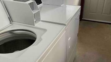 A laundry room with stacked washers and dryers, a power outlet, and a door with a window.
