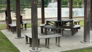 A gazebo with picnic tables by a lake.