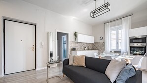 Un salon moderne comprenant un canapé, une table à manger et un coin cuisine avec un four.