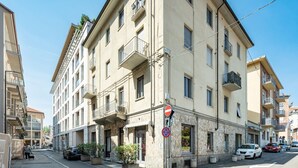 Un immeuble à plusieurs étages doté de balcons, un panneau indiquant qu’il est interdit de se garer et un marquage « STOP » sur la chaussée.