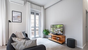 Un salon moderne avec un canapé, un téléviseur et une plante.