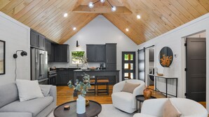 A modern loft-style living space with a kitchen, dining area, and seating. - Your Fall Getaway is here - Modern Luxury Cabin -  Kings Beds - Hot tub (Cherry Log)