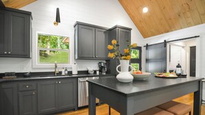 A modern kitchen with grey cabinets, a black countertop, a white vase with flowers, and a wooden ceiling. - Your Fall Getaway is here - Modern Luxury Cabin -  Kings Beds - Hot tub (Cherry Log)