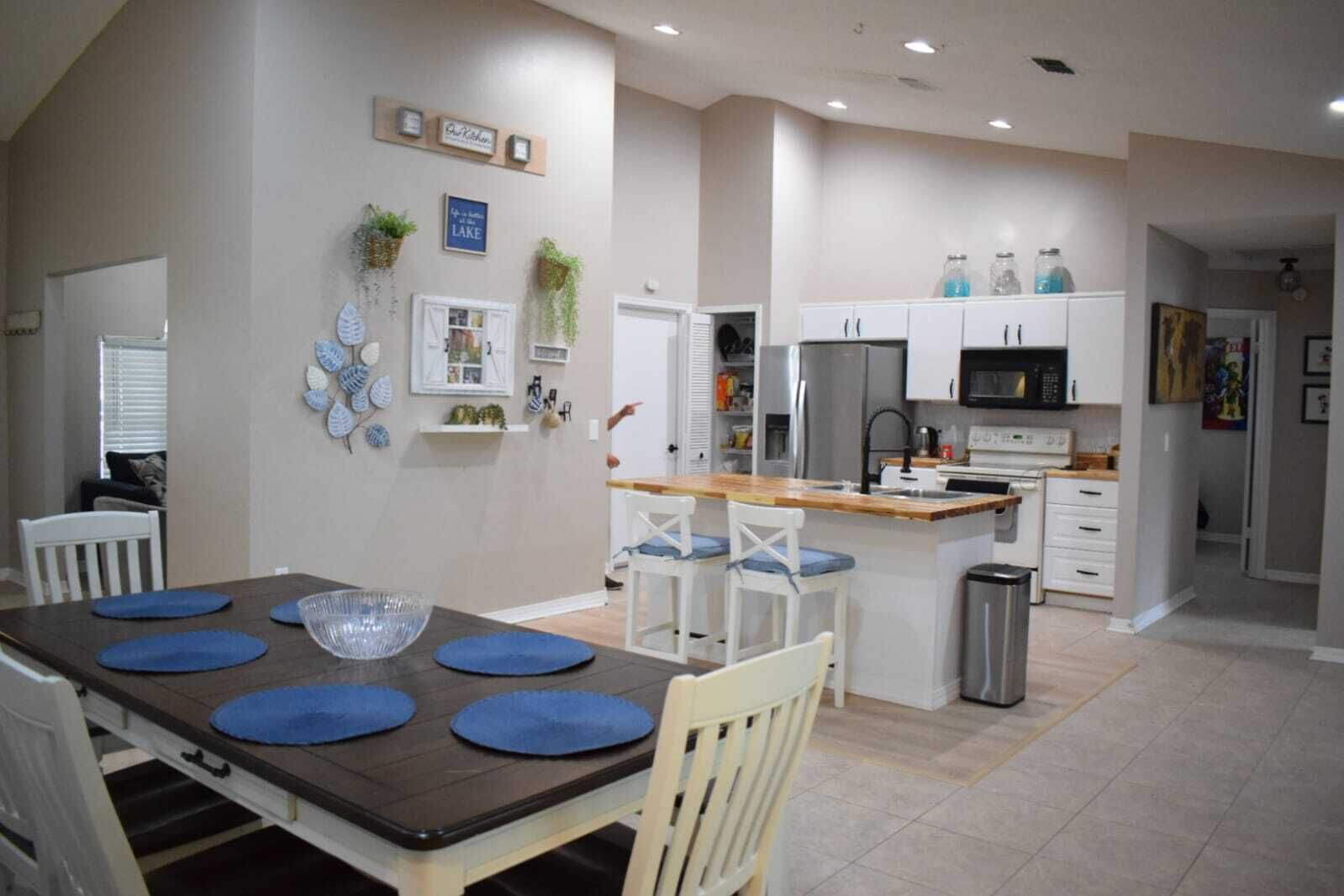 A modern kitchen with white cabinets, stainless steel appliances, and a wooden island with bar stools.