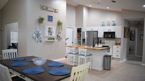 A modern kitchen with white cabinets, stainless steel appliances, and a wooden island with bar stools. - Zojo_ Lovely House Close TO Disney (Clermont)