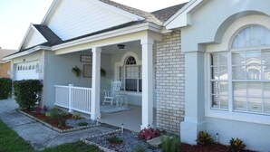 A single-story house with a covered porch, a brick exterior, and a garage door. - Zojo_ Lovely House Close TO Disney (Clermont)