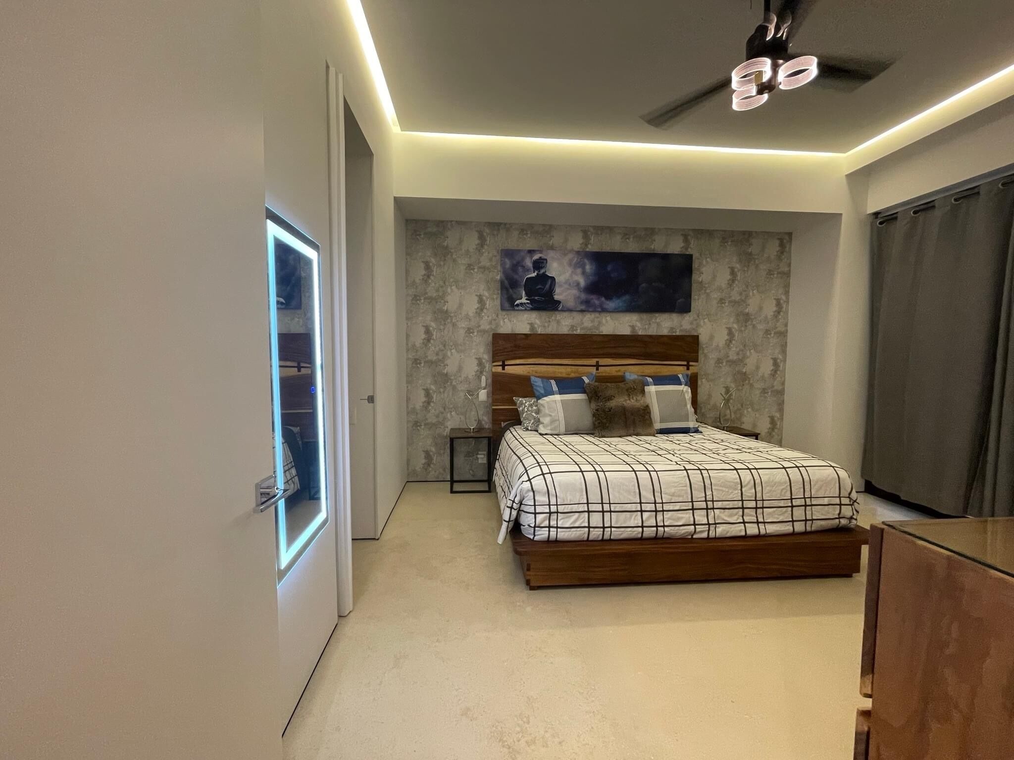 Une chambre moderne avec un grand lit, un ventilateur de plafond et un tableau au mur.