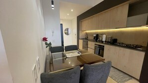 A modern kitchen with a dining area, including a table and chairs, a vase with a flower, and a coffee machine. - SOHO PV PUERTO VALLARTA  (Puerto Vallarta)