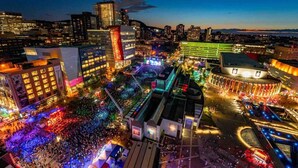 A cityscape at dusk with illuminated buildings and a crowded square. - #202_Downtown's Exquisite Luxury Studio (Montreal)