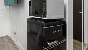 A modern kitchen with a black refrigerator, a microwave, and a flat-screen TV mounted on the wall. - #202_Downtown's Exquisite Luxury Studio (Montreal)