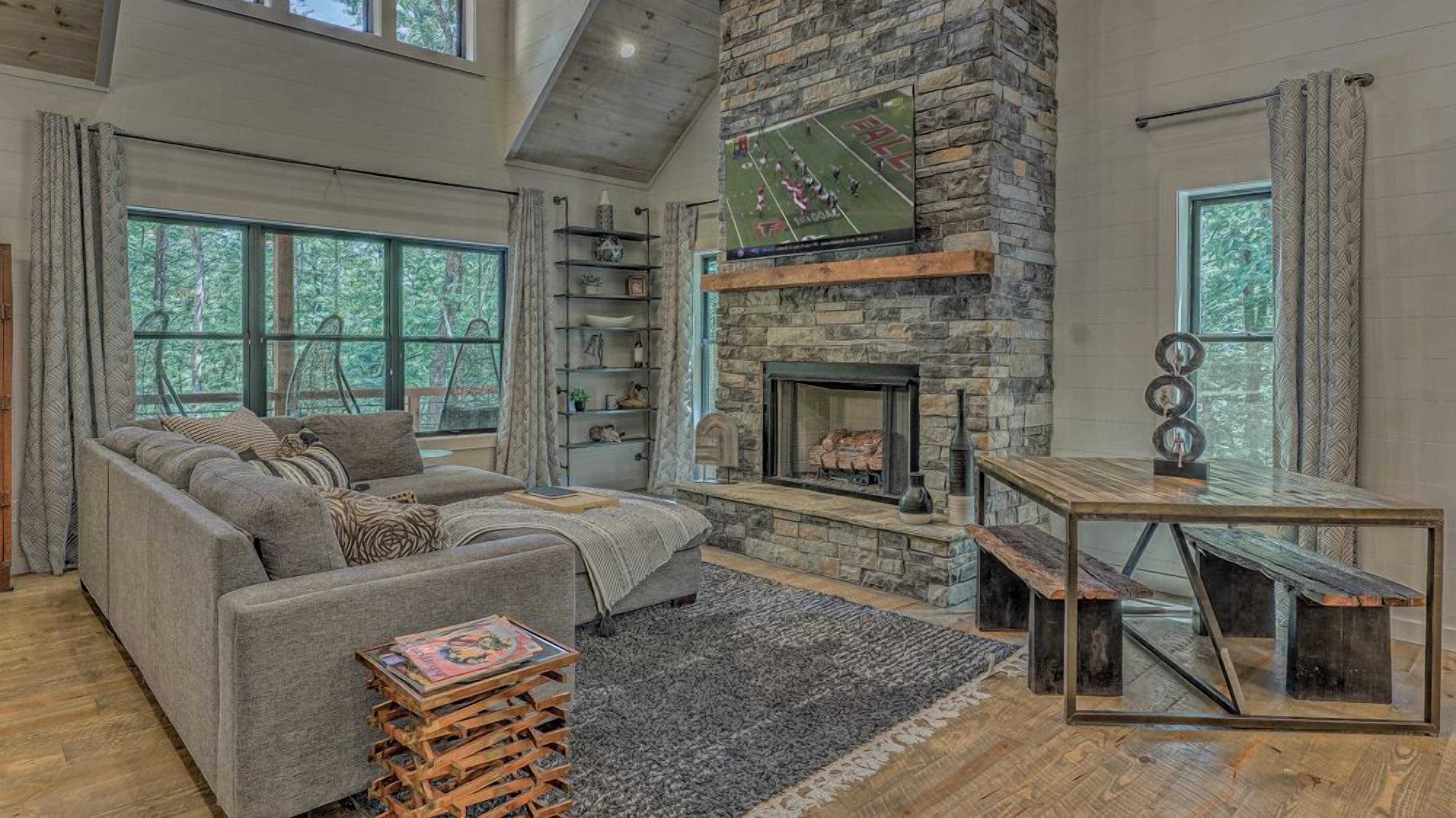 A cozy living room with a stone fireplace, a sofa, a coffee table, and a bookshelf.