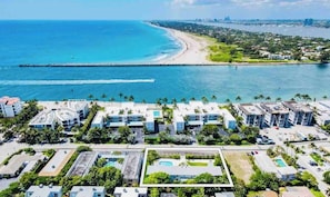 Vista aerea di un resort costiero con diversi edifici, una spiaggia e un molo.
