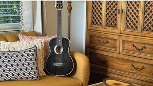 A living room with a sofa, patterned pillows, a guitar, a wooden cabinet, and a glass coffee table. - Fernando Flats: Boutique 1-Bed Beach Flat 1 (Palm Beach Shores)