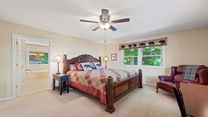A bedroom with a bed, a chair, a ceiling fan, a window with a view, and a door. - 4,000ft in Elevation with Layered Mtn Views, HOT TUB, Wifi, Firepit, and privacy (Waynesville)