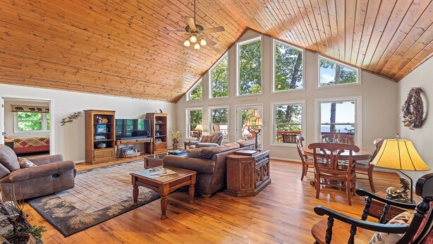 A spacious living room with a high ceiling, wooden floors, and large windows offering views of the outdoors. - 4,000ft in Elevation with Layered Mtn Views, HOT TUB, Wifi, Firepit, and privacy (Waynesville)