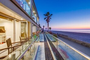 A modern hotel balcony with a glass railing overlooking the ocean at sunset. - Ocean Front * 2 Levels * Exclusive patio (San Diego)