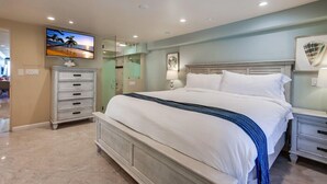 Une chambre d’hôtel avec un grand lit, un téléviseur fixé au mur, une commode et une table de chevet.