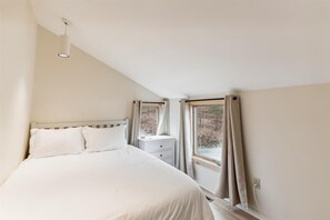 Relax in this serene bedroom with a single bed and a view of the outdoors through the partially open window.