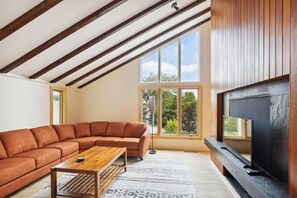 Relax in this stylish living room with a high ceiling, large windows, and a comfortable sofa.