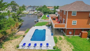 A residential property with a swimming pool, lounge chairs, and a view of a water body. - Saltwater Charm | 995 ft. to the Beach | Private Pool (Virginia Beach)
