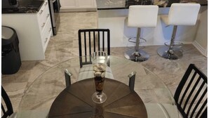 A modern kitchen with white cabinets, a black countertop, and a dining area with a round table and four chairs. - Cozy Niagara Retreat ,15 min drive to Niagara Falls, 4 bdrms, sleeps up to 9 (Thorold)