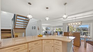 Een moderne keuken met een groot eiland, houten kastjes en hanglampen.