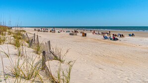 Een breed zandstrand met mensen die ontspannen en zonnebaden.